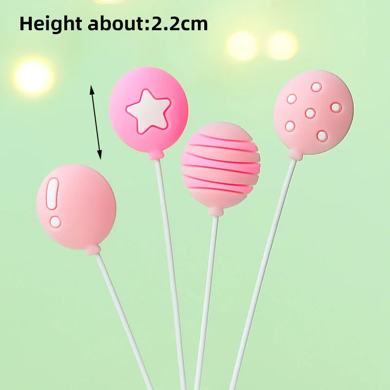 Three pink balloon cake toppers, including a star and striped spheres, are shown against a light green background.