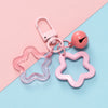 A pink star-shaped charm pendant keychain with a silver clasp and a round bead on a light blue background.