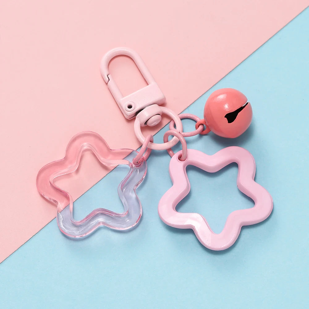 A pink star-shaped charm pendant keychain with a silver clasp and a round bead on a light blue background.