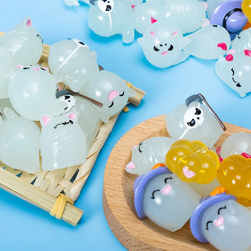 A collection of seven translucent white and pink luminous ghost resin ornaments displayed on a wooden surface.