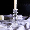 Elegant clear glass pillar candle holder with a white candle resting on a draped cloth.
