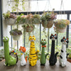 A collection of cat-shaped resin vases in various colors and sizes sitting on a wooden surface.