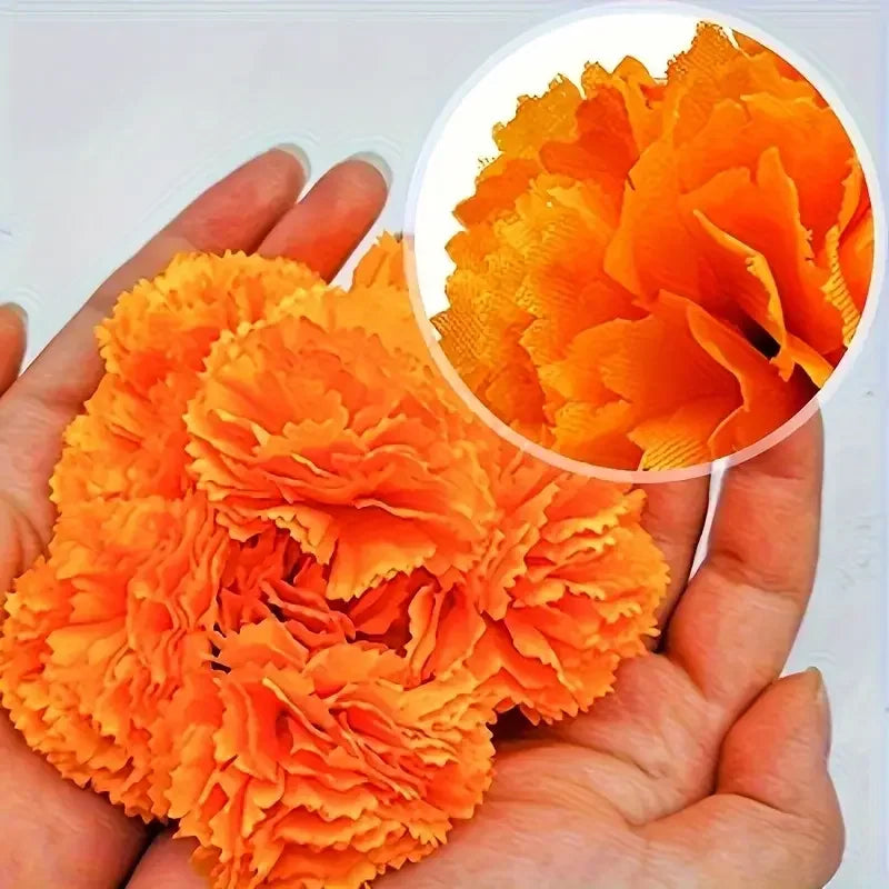 A hand holds a vibrant set of artificial orange marigold and carnation flowers for festive decoration.