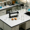 A white laboratory table displaying various glass vials, pipettes, and small wooden samples for a miniature set.