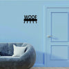 A light blue wall features a metal sign spelling 'WOOF' next to a light blue door and a gray sofa.