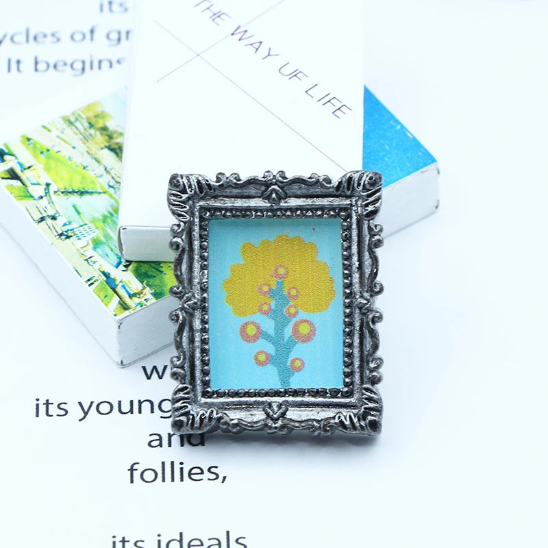 A miniature framed piece of art featuring a yellow tree against a light blue background.