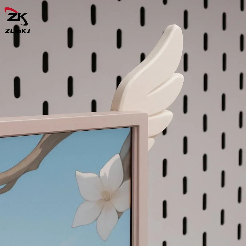 A close-up view of a light pink monitor wing decoration with white, stylized feathers against a patterned wall.