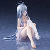 A figurine of an anime girl with light blue hair sitting down, wearing a pink dress and white stockings.