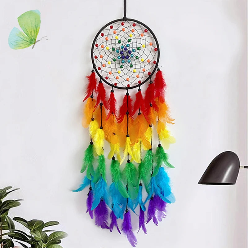 A colorful feather dream catcher with a beaded center and long dangling feathers is displayed on a white wall.