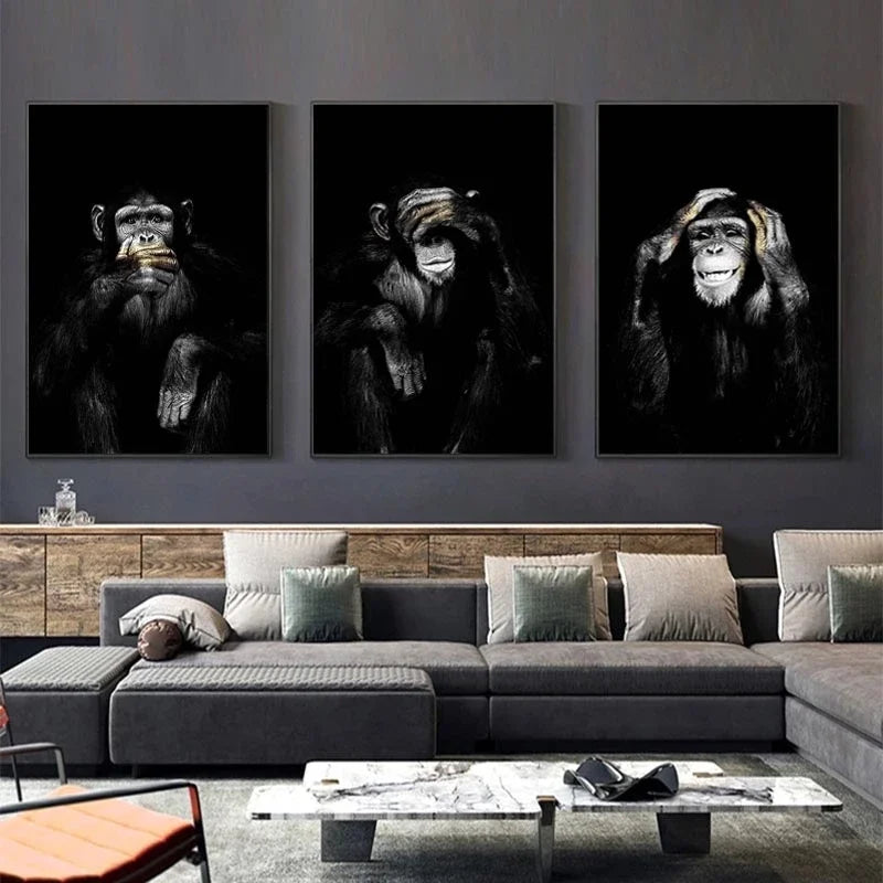 A set of three black and white canvas prints featuring portraits of monkeys displayed on a gray sofa.