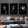 A set of three black and white canvas prints featuring portraits of monkeys displayed on a gray sofa.
