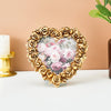 A heart-shaped frame made of gold-colored roses surrounds a clear resin photo with pink and green floral designs.