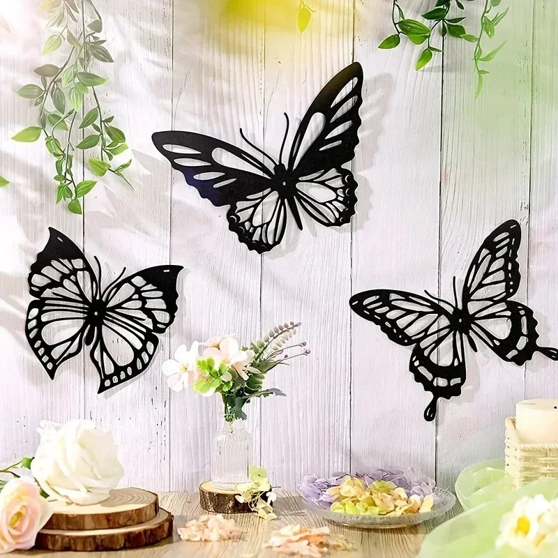 A set of three black metal butterfly wall art pieces displayed against a white wooden background.