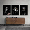 Three framed black and white canvas prints of monkeys displayed above a wooden cabinet.