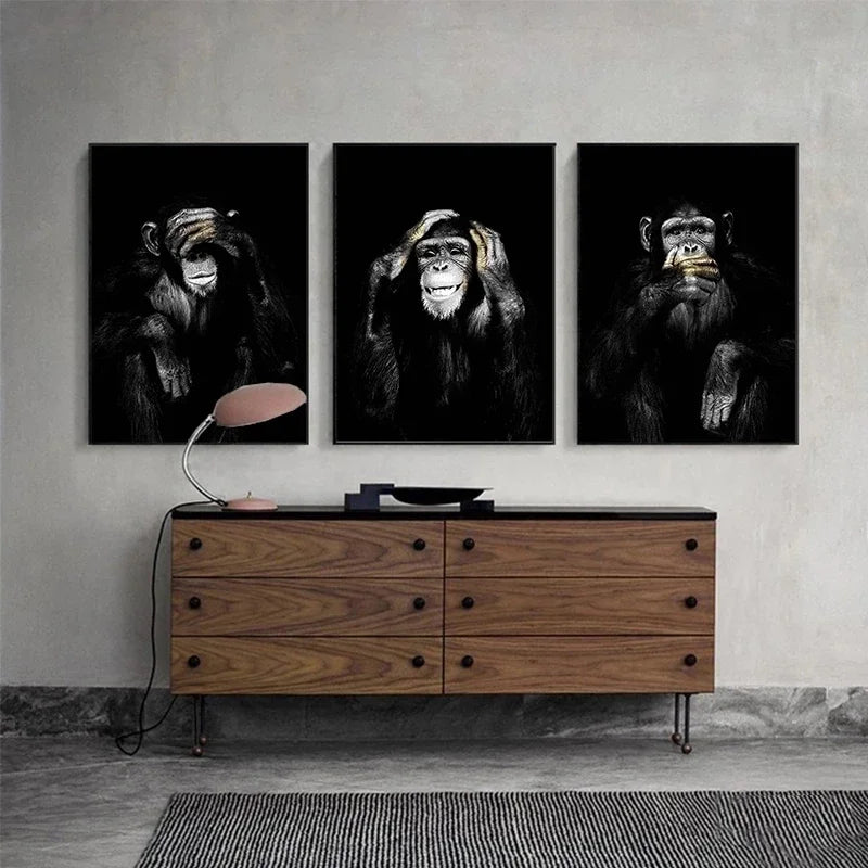 Three framed black and white canvas prints of monkeys displayed above a wooden cabinet.