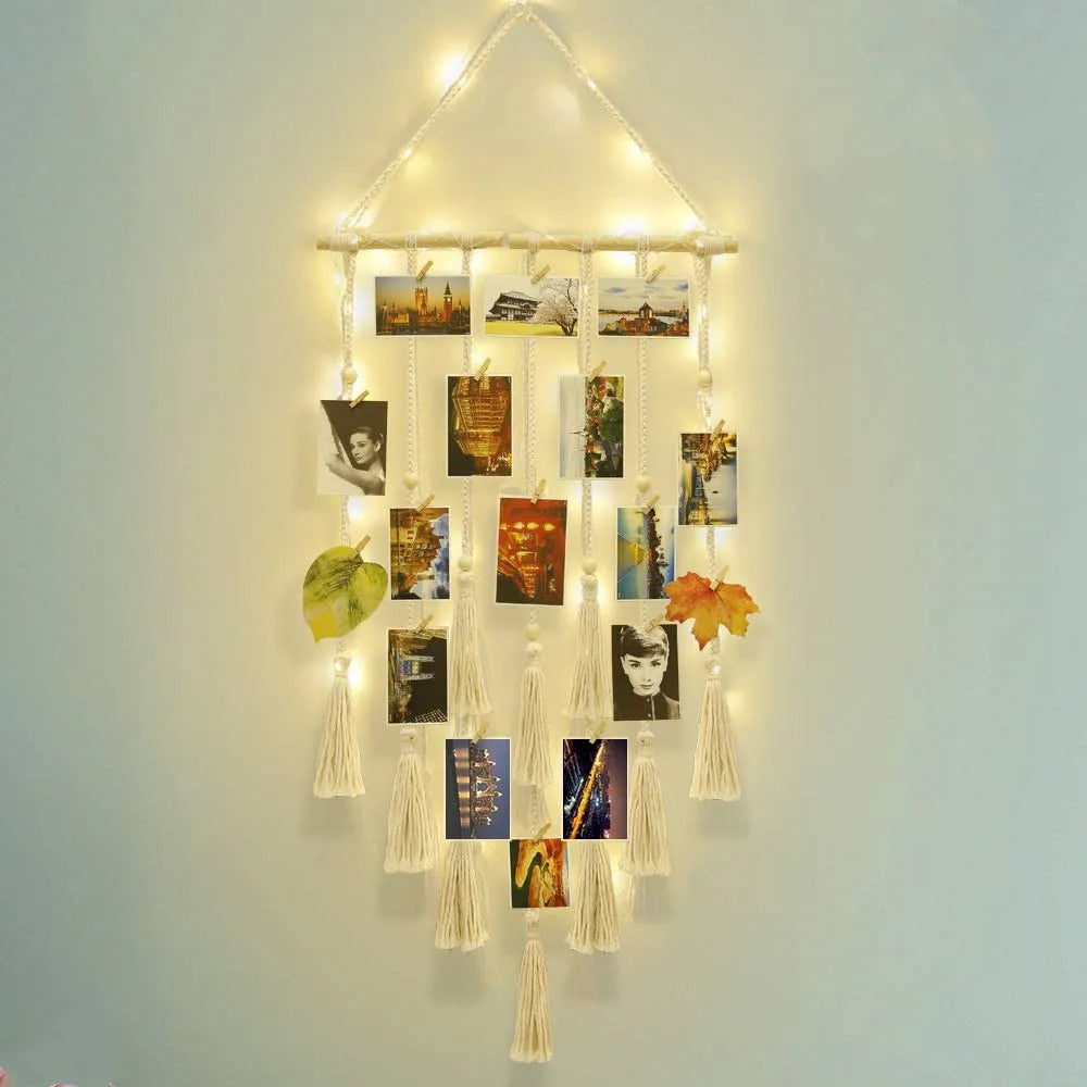 A bohemian macrame photo display featuring multiple framed photos hanging from a string on a light blue wall.