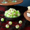 A bowl of glow-in-the-dark green and white eyeball bouncy balls resting on a dark fabric.