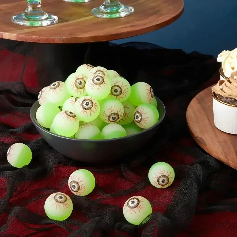 A bowl of glow-in-the-dark green and white eyeball bouncy balls resting on a dark fabric.
