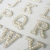 A collection of white alphabet letter rhinestone patches including C, K, P, Q, R, and V.