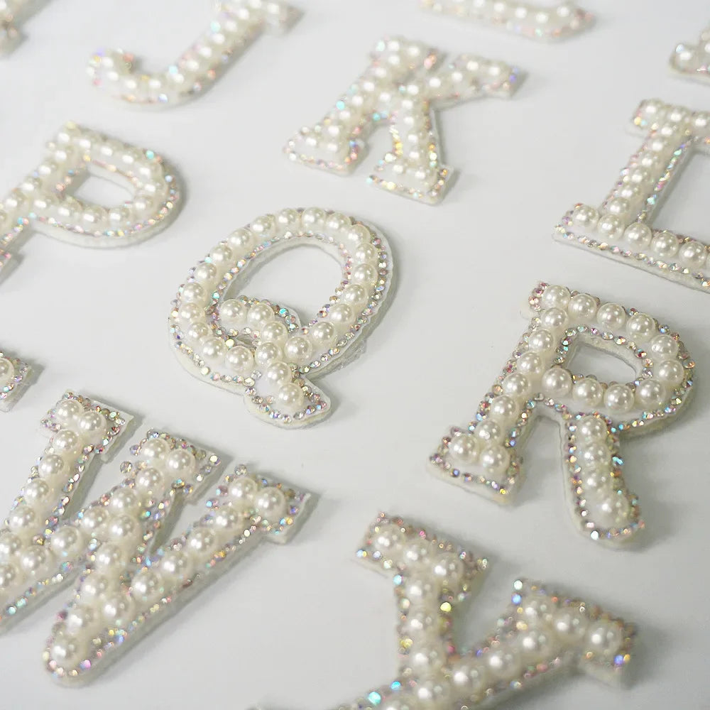 A collection of white alphabet letter rhinestone patches including C, K, P, Q, R, and V.