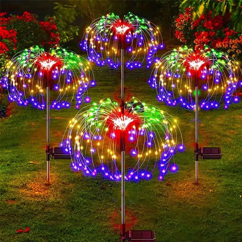 Affichage de feux d'artifice solaires LED colorés illuminant un jardin en herbe la nuit.