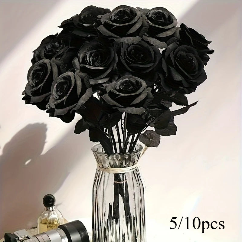 A bouquet of artificial black roses in a glass vase with shadows cast on a white surface.