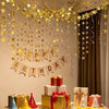 A shimmering gold star paper garland hangs above a table decorated with gift boxes and party accents.