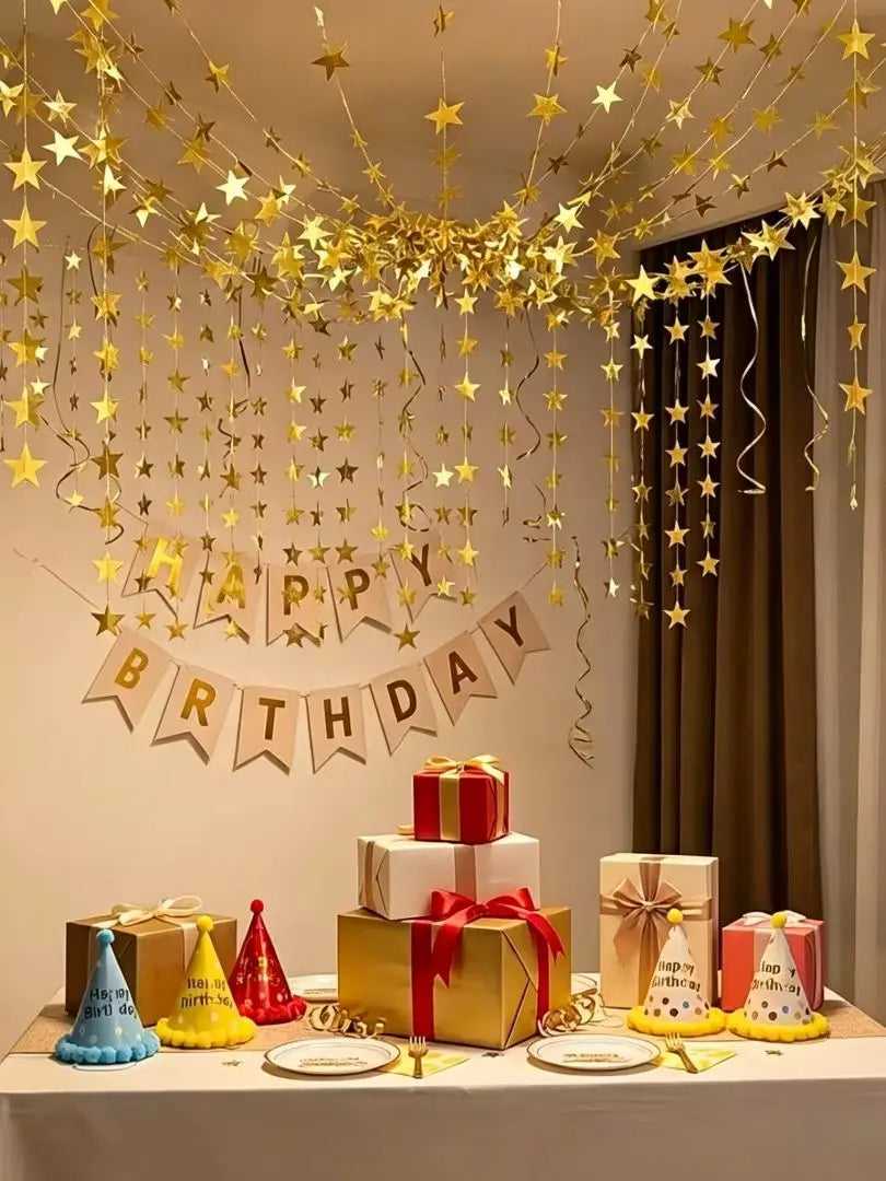 A shimmering gold star paper garland hangs above a table decorated with gift boxes and party accents.