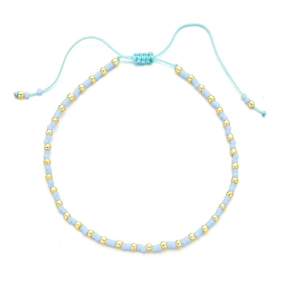Handmade boho glass bead bracelet with adjustable cord featuring light blue and gold beads