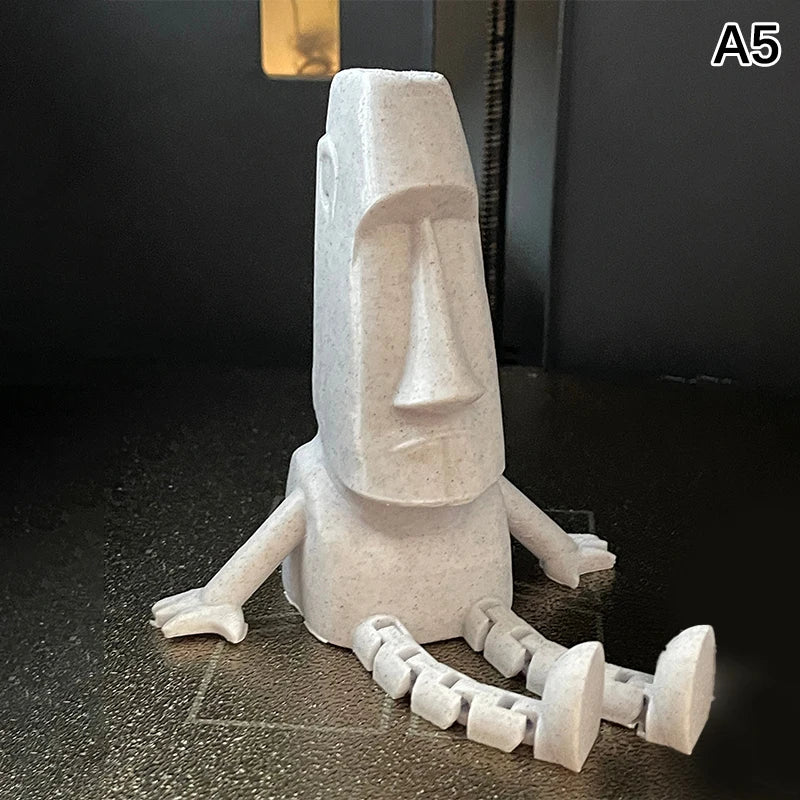 A white 3D printed Moai statue figurine with movable joints shown against a dark background.