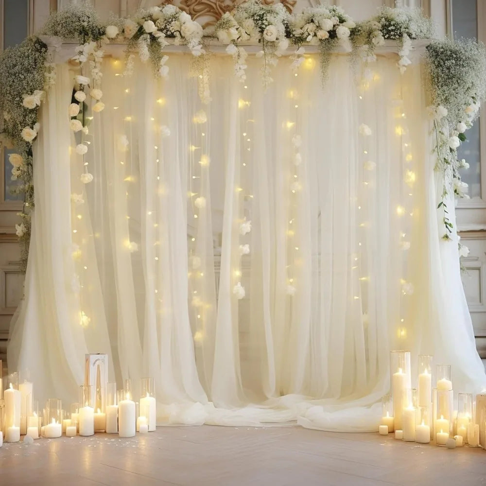 Elegant white wedding tulle backdrop decorated with cascading flowers and warm string lights