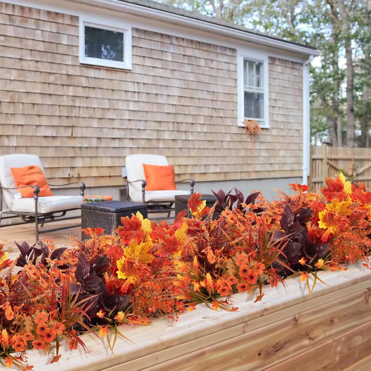 Künstlicher Blumen-Girlanden-Satz mit leuchtend orange, rot und gelbem Laub auf einer Holzpflanzbox.
