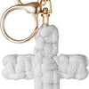 A bohemian woven white cross keychain with a gold-toned split ring and clasp.