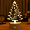 A glowing acrylic Christmas tree silhouette featuring a skull, bell, and star design on a wooden surface.