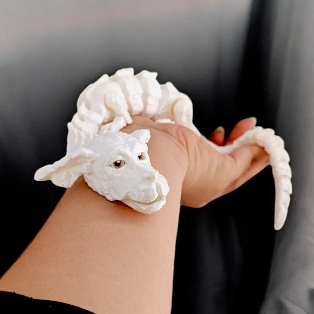 Une figurine de dragon blanc réaliste est tenue au poignet d'une personne.