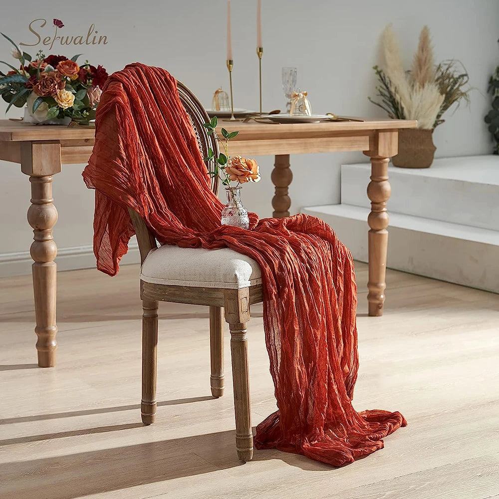 A vibrant orange-red fabric draped over a wooden chair next to a rustic dining table.