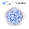 A collection of light blue silicone heart beads in various shapes is displayed in a white dish.
