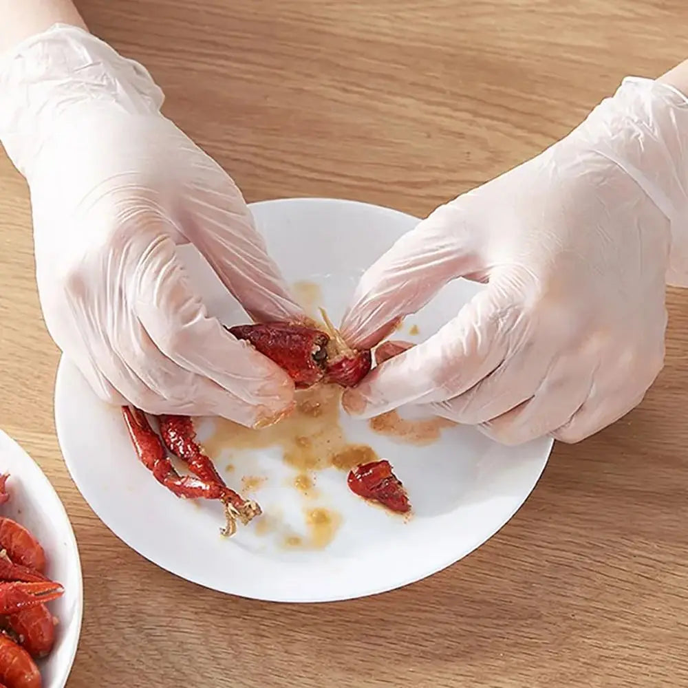 Hands wearing disposable safety gloves are handling dried red chili peppers on a white plate.