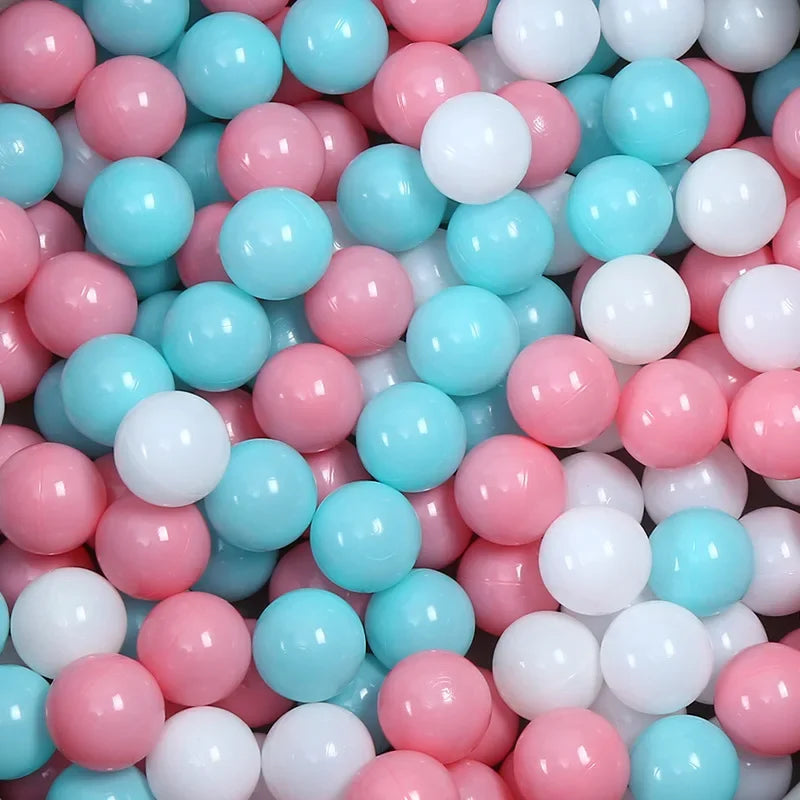 A pile of colorful, round plastic balls in pink, white, and light blue for play areas.