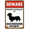 A vintage tin sign with a red and white warning that reads BEWARE PROPERTY PATROLLED BY DACHSHUND SECURITY