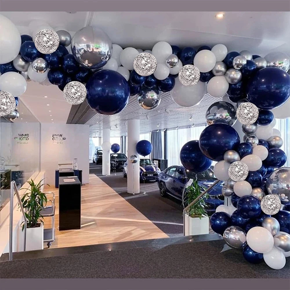 A balloon garland arch display featuring navy blue, silver, and white balloons in a modern interior setting.
