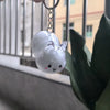 A clear, round rabbit charm hangs from a silver chain against a blurred background.