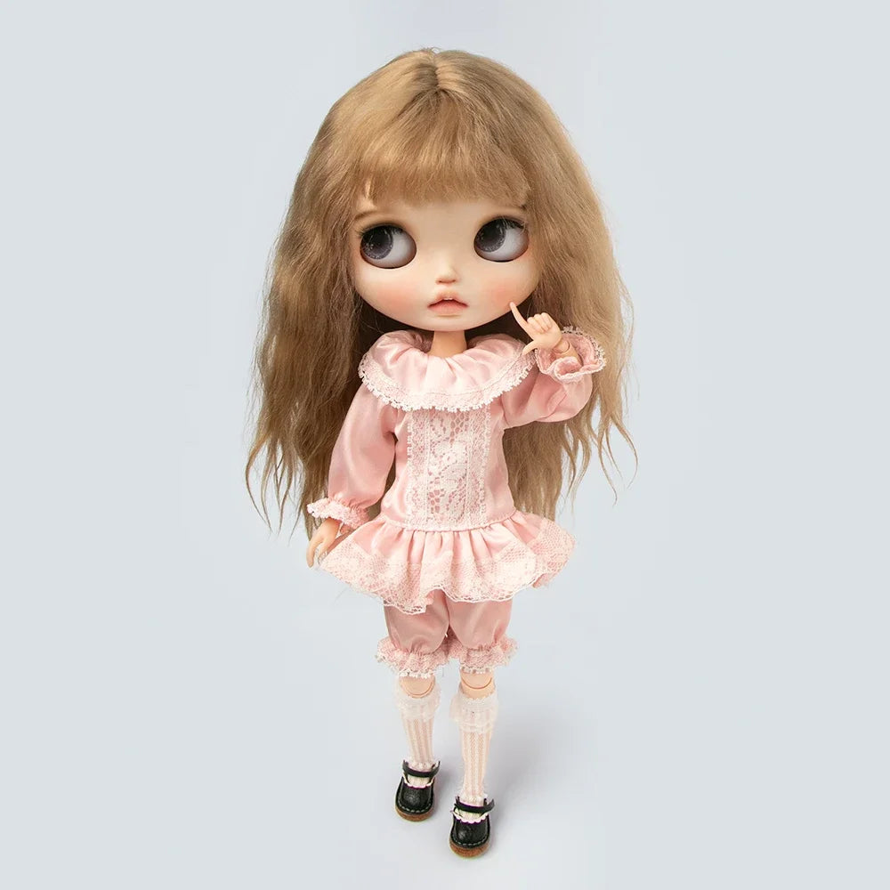 A vintage lace pajama set for a doll featuring pink fabric and delicate lace trim.