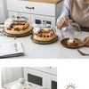 A solid acacia wood cake tray with a glass dome cover is displayed on a white table.