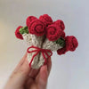Hand-crocheted red and white rose flower coasters displayed in a hand.