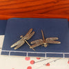 Vintage brass dragonfly desk decor resting on a dark blue coaster.