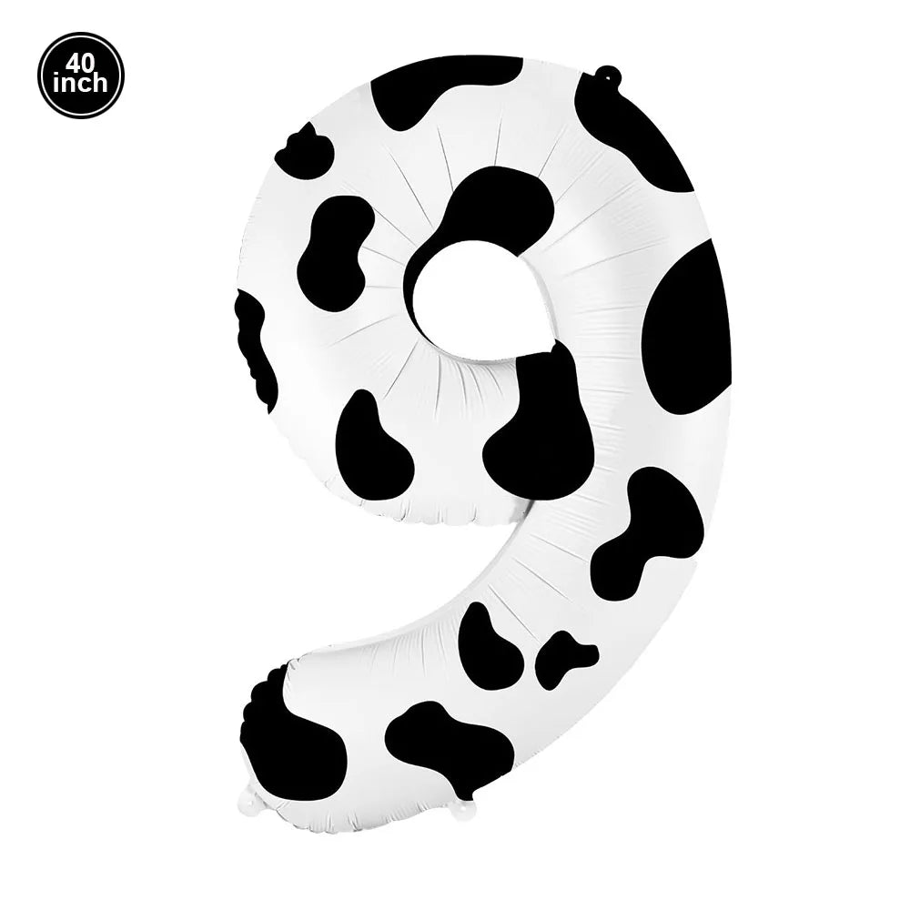A white foil balloon shaped like the number nine with a black cow print pattern.