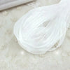 White decorative fishtail yarn ribbon coiled and flowing on a light surface.
