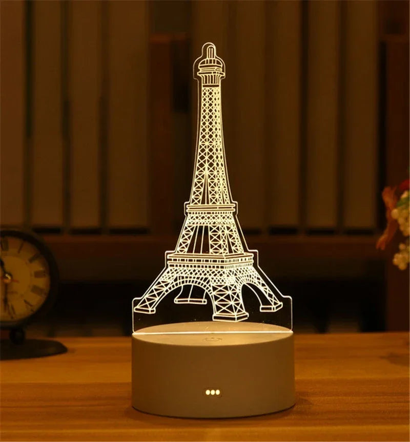A white acrylic silhouette of the Eiffel Tower is displayed on a round base, illuminated by an LED light.