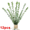 A bundle of artificial eucalyptus stems with green leaves tied together with twine.
